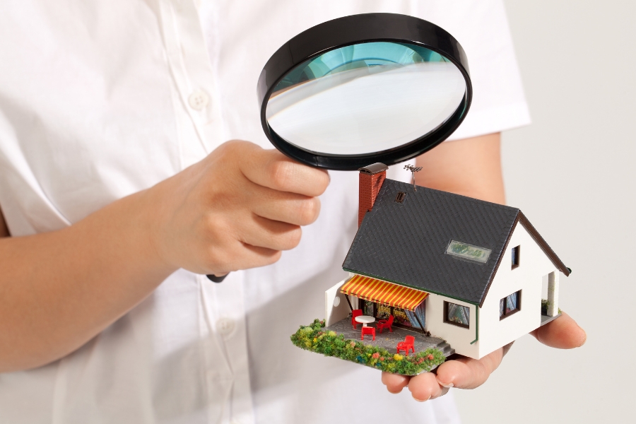 man close up with magnifying glass looking at toy house longwood fl